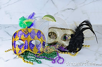 Alcoholic beverage and pourple, green and gold Mardi Gras beads with mask on a marble table for a festive February holoiday image Stock Photo