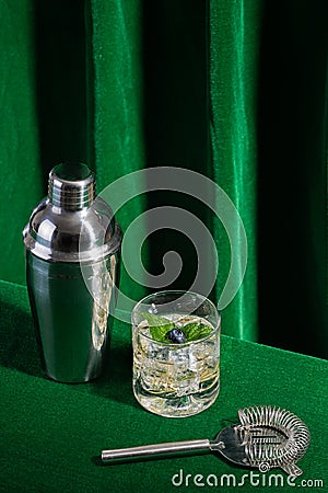 alcoholic drink with blueberry and mint leaf, with mixology utensils on green background for bartender Stock Photo