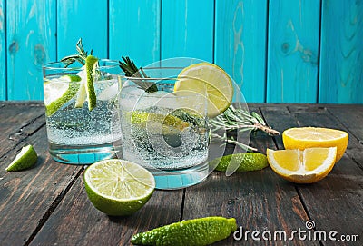 Alcoholic drink gin tonic cocktail with lemon, rosemary and ice on rustic wooden table Stock Photo