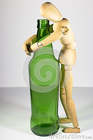 Alcoholism, alcohol addiction, social problem: a wooden dummy, a lonely drunkard, an alcoholic, hugging a bottle of beer Stock Photo