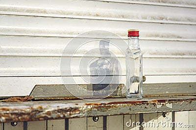 Alcoholism problem concept picture of empty vodka bottle on dirty windowsill white kiosk background plastic view slum ghetto urban Stock Photo