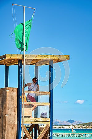 Alcudia, Spain 14.09.2011 - Lifeguard in booth observing people swimming at Playa de Muro beach. Mallorca island famous tourist Editorial Stock Photo