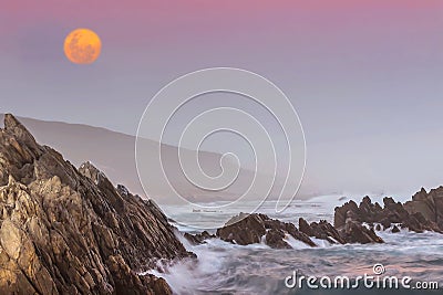 A pink full moon sunset on the wild rocky Indian Ocean coastline of Port Elizabeth, South Africa Stock Photo