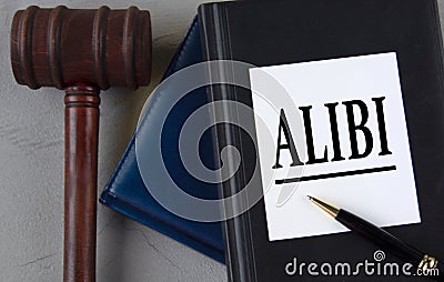 ALIBI - word on a white sheet with leather notebooks, a judge's hammer and a pen Stock Photo