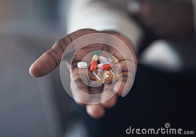 All my vitamins are accounted for. an unrecognizable man sitting alone in his living room and holding his medication in Stock Photo