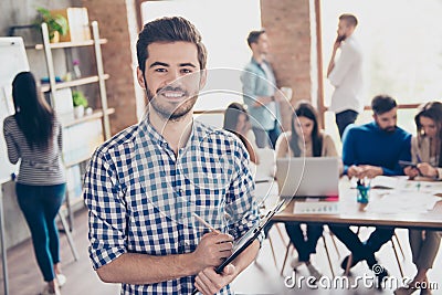 All for one and one for all! Leadership. Successful stylish young bearded man in casual checkered shirt is standing in the office Stock Photo