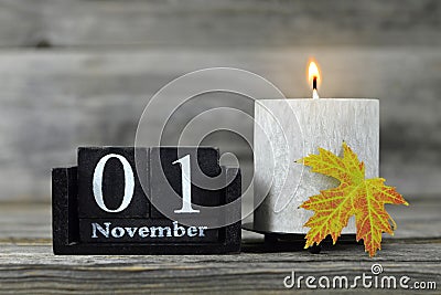 All Saints Day. Burning candle, wooden calendar and yellow autumn leaf Stock Photo