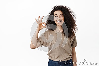 All under control. Smiling young woman assure everything OK, showing okay sign and say yes, approve or agree, recommend Stock Photo