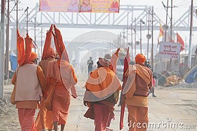 A team of Hindu Sadhus wearing saffron clothes walking on the pilgrim route to holy Sangam. Editorial Stock Photo