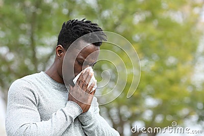 Allergic black man blowing on wipe in a park on spring season Stock Photo