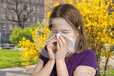 Allergy concept. Young allergic woman is sneezing and blowing her nose. Stock Photo