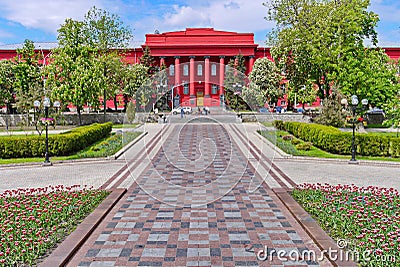 Alley leads to an unusual bright red building with columns Stock Photo