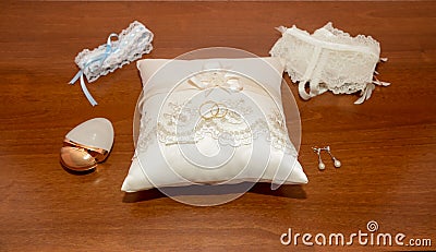 Alliances on a small fabric cushion surrounded by different bridal accessories for the wedding day. Stock Photo