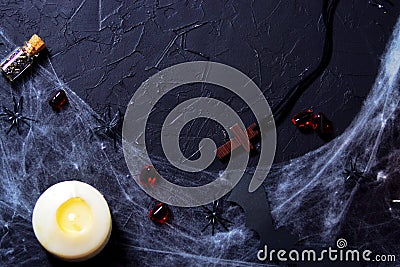 alloween wooden cross lying next to a burning candle on a web with spiders and bats on a black background. horizontal, flat lay, Stock Photo