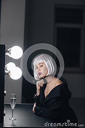 Alluring blonde woman drinking champagne in dressing room Stock Photo