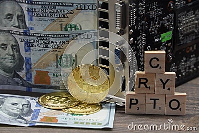 Almaty, Kazakhstan - 04.04.2023 : The bitcoin coin is on the table next to the dollars, the inscription: crypto and a video card Editorial Stock Photo