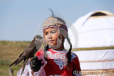 Almaty / Kazakhstan - 09.23.2020 : A little girl in Kazakh national dress holds a Balaban Falcon in her arms Editorial Stock Photo