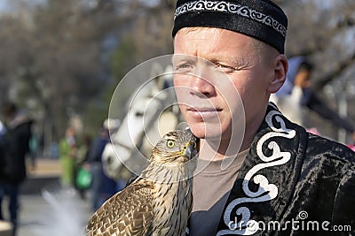 Falcon sits on the hand of a hunter dressed in the national Kazakh clothes - berkutchi. Editorial Stock Photo