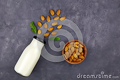 Almond milk in bottle and almond nuts on dark grey background, top view. Non-dairy lactose free milk with nuts Stock Photo