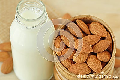 Almond milk in bottle with almonds in wooden bowl Stock Photo