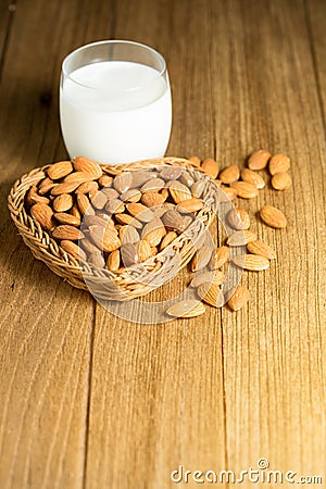 Almond milk in glass with almonds in basket heart shape Stock Photo