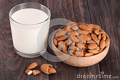 Almond milk in a glass and almonds in a bowl on dark wooden background Stock Photo