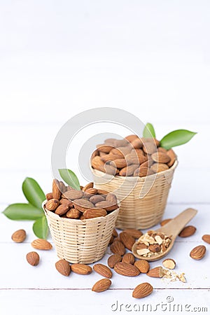 Almond nuts in basket with wood spoon isolated on white wooden background, Almonds are healthiest nuts and one of the best brain Stock Photo