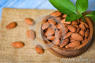 Almonds nuts on wooden bowl with leaf almonds top view on sack background - Roasted almond for snack Stock Photo