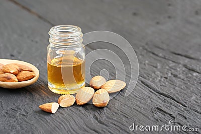Almonds oil and pile of roasted almonds on black wooden board. Stock Photo