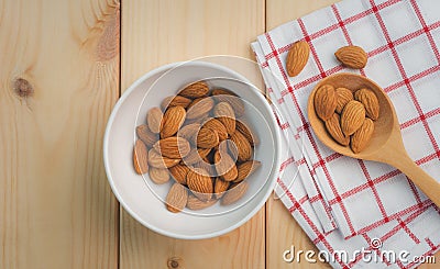 Almonds in white porcelain bowl with wooden spoon Stock Photo