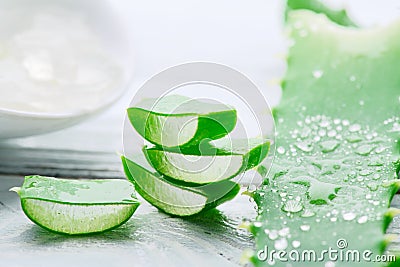 Aloe Vera gel closeup on white wooden background. Organic sliced aloevera leaf and gel, natural organic cosmetic ingredients Stock Photo