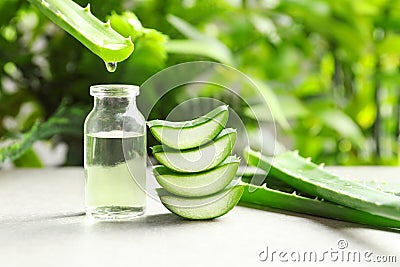 Aloe vera juice dripping from leaf into bottle on table Stock Photo