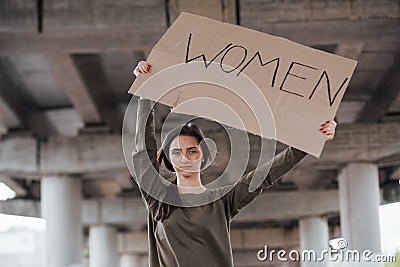 Alone in the area. Pretty girl in casual clothes stands with handmade feminist poster in hands Stock Photo