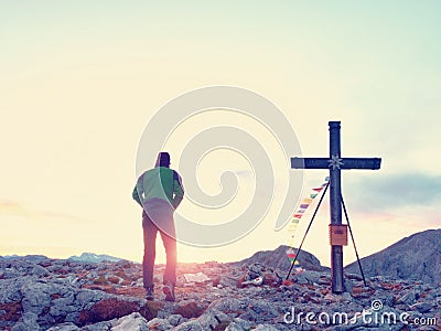 Alone man climber near the summit cross on peak, Dolomite Alps, Austria. Sunny windy evening. Stock Photo