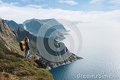 Alone professional traveler with backpack on high mountain standing on the edge cliff rock and looking away Stock Photo