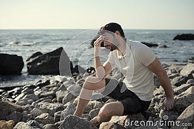 Alone sad man sitting on a sea beach Stock Photo