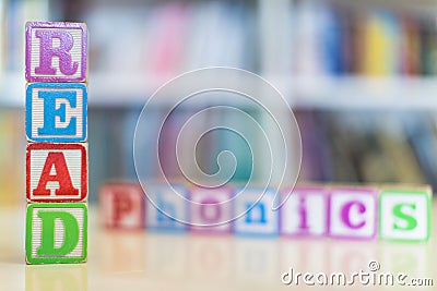 Alphabet blocks spelling the words read and phonics in front of a bookshelf Stock Photo