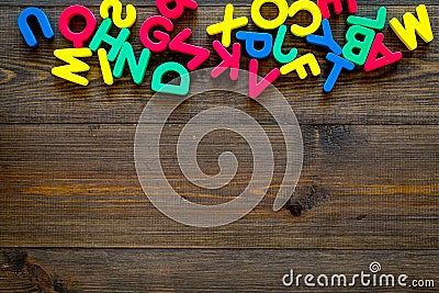 Alphabet for kids concept. English letters in disorder on dark wooden background top view copy space Stock Photo