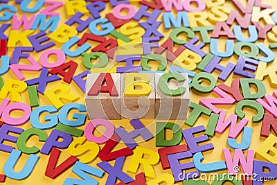 Alphabet on wooden tiles and ABC on a cube against yellow background Stock Photo