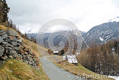 Alpine landscape with dirt road along the mountain slope Stock Photo