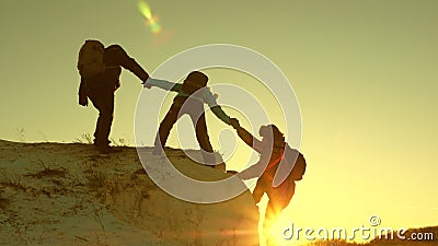 Team of climbers climbs a mountain holding out a helping hand to each other. Free woman traveler climb mountain Stock Photo