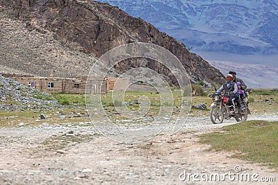 Altai, Mongolia - June 14, 2017: Mongolian men ride motorbike at steppe field on mountain background Concept authentic local asian Editorial Stock Photo