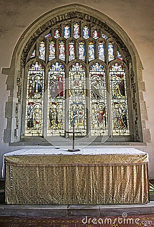 Altar and beautiful stained glass window of ancient St Mary`s Church Pevensey Editorial Stock Photo