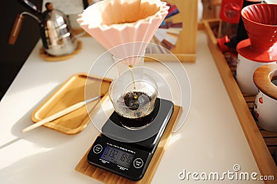 Alternative manual coffee brewing. Pink ceramic origami dripper on electronic scale Stock Photo