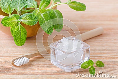 Alternative natural toothpaste coconut oil and wood toothbrush closeup, mint on wooden Stock Photo