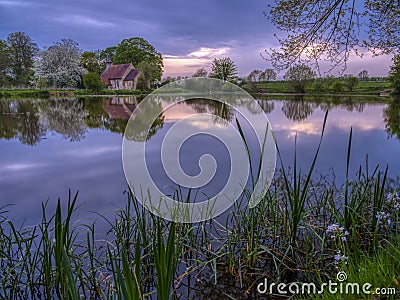 Reflections of St Leonard`s church in Hartley Mauditt Pond, South Downs National Park, UK Stock Photo