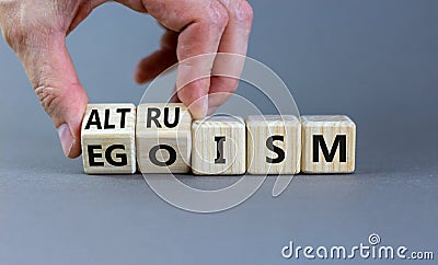 Altruism or egoism symbol. Businessman turns wooden cubes and changes the word `egoism` to `altruism`. Beautiful grey backgrou Stock Photo