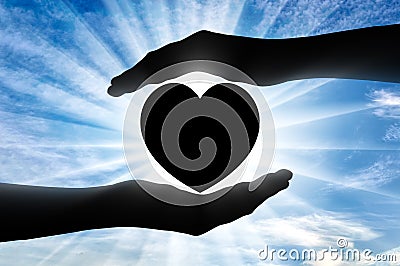 Altruism. Silhouette of hands protecting heart symbol Stock Photo