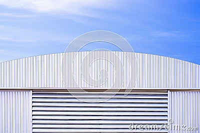 Aluminium louver on corrugated steel wall of warehouse building with curve metal roof against blue sky background Stock Photo