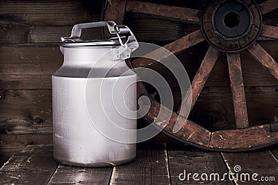 Aluminium water can and old wheel Stock Photo